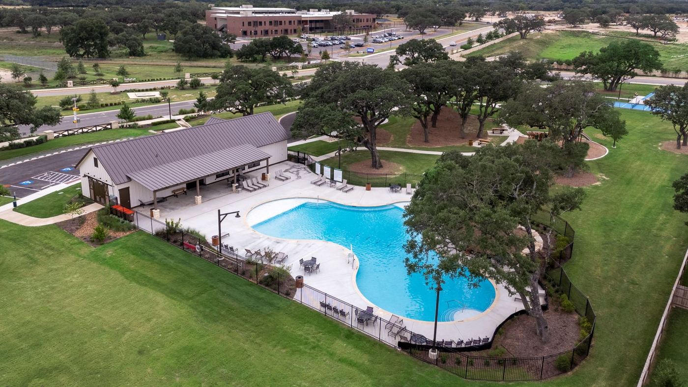 The amenity area from above — walks, metal fencing and stone walls set around the preserved oaks.