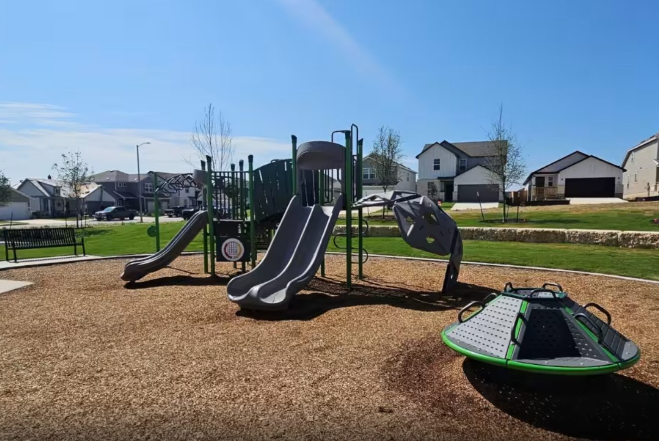 Playground with landscape benches, sidewalks and a limestone retaining wall.
